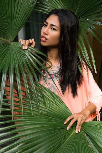 Portrait of beautiful thai woman over tropical leaves. Spa and relax concept. Ethnic boho style.