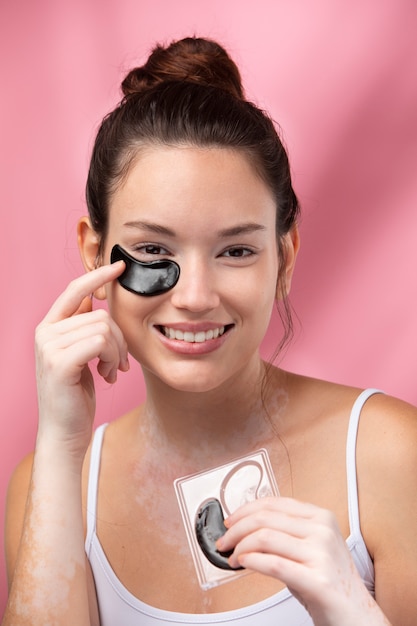 Free photo portrait of a beautiful woman applying an under eye patch