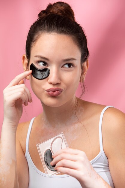 Portrait of a beautiful woman applying an under eye patch