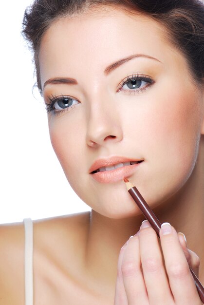 Portrait of beautiful woman applying lipstick using lip concealer brush