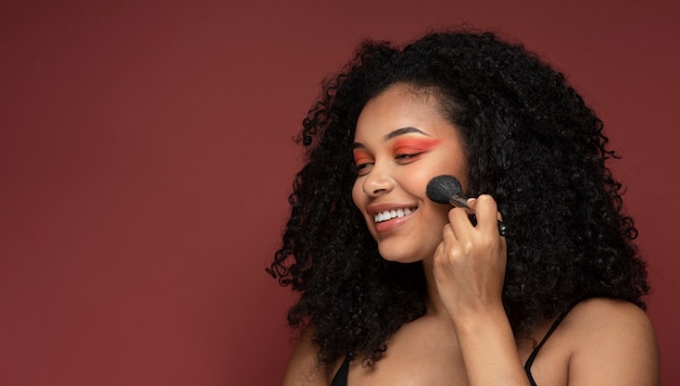 Portrait of a beautiful woman applying make-up on her face