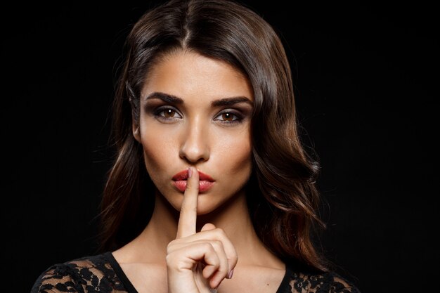 Portrait of beautiful woman in black dress over dark wall