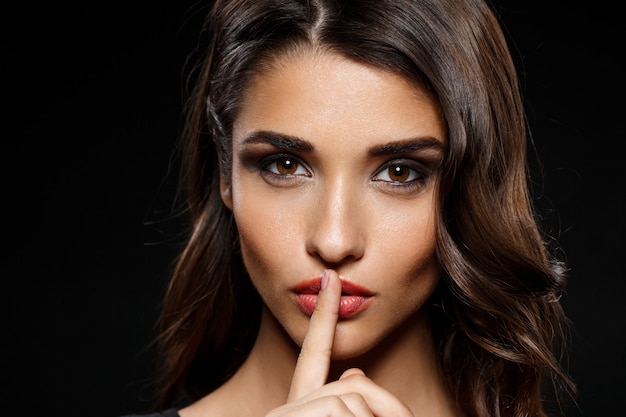 Portrait of beautiful woman in black dress over dark wall