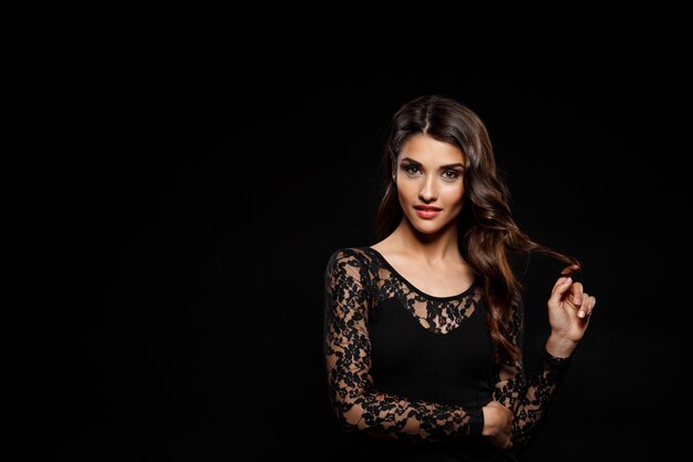 Portrait of beautiful woman in black dress over dark wall