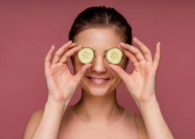 Portrait of beautiful woman covering her eyes with cucumber slices