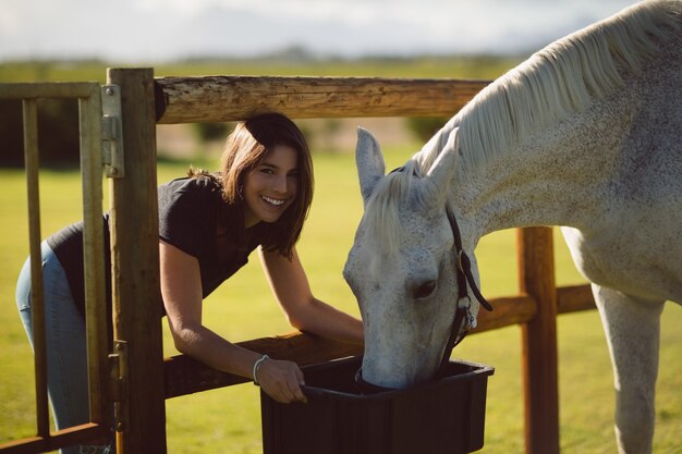 Portrait of beautiful woman feeding horse in farmland