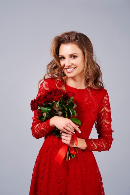 Portrait of beautiful woman holding a bunch of red roses