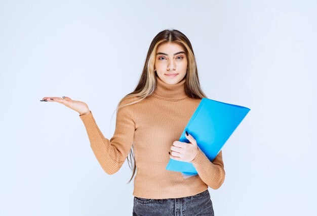 Portrait of a beautiful woman holding a folder against white wall .