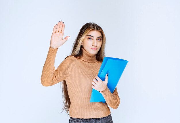 Portrait of a beautiful woman holding a folder against white wall .