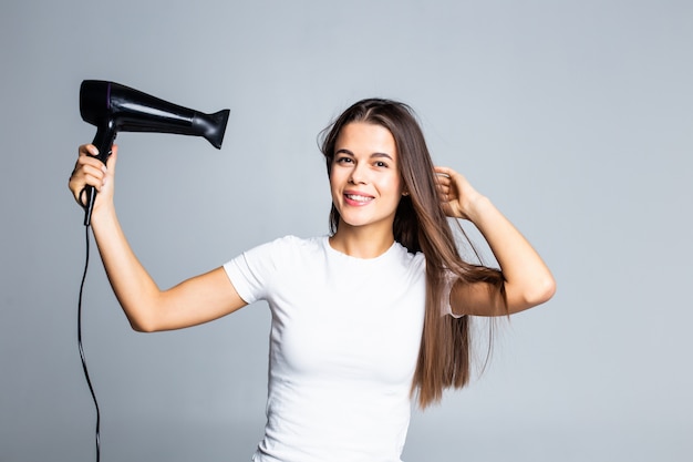 Portrait of beautiful woman holding hair dryer isolated on gray