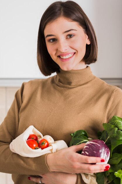 Foto gratuita ritratto di bella donna che tiene le verdure organiche