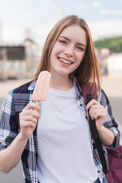 Портрет красивой женщины, держащей мороженое эскимо