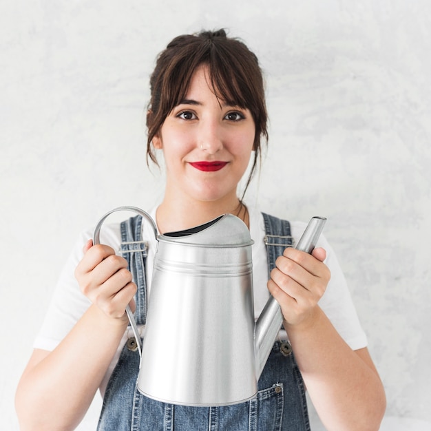 Free photo portrait of a beautiful woman holding watering can