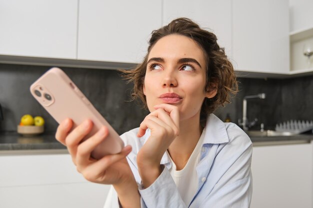 Портрет красивой женщины дома, держащей смартфон, онлайн-покупки из приложения для мобильных телефонов