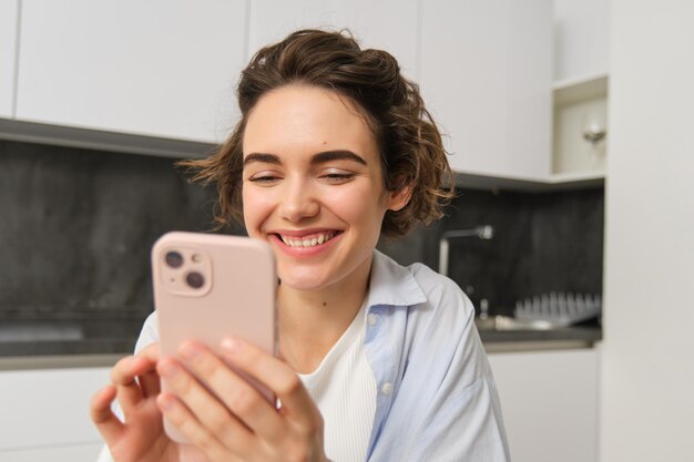 Portrait of beautiful woman at home holding smartphone online shopping from mobile phone app