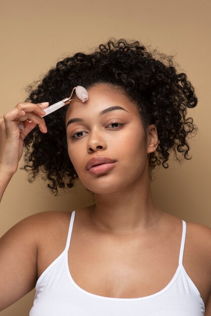 Portrait of a beautiful woman massaging her face with a massage roller