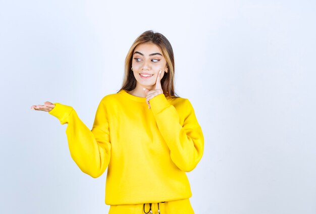 Портрет красивой женщины модели стоя и позирует в желтой футболке
