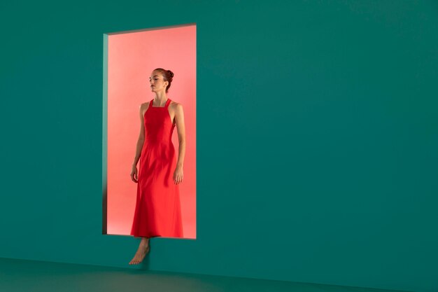Портрет красивой женщины, позирующей в струящемся красном платье с копией пространства