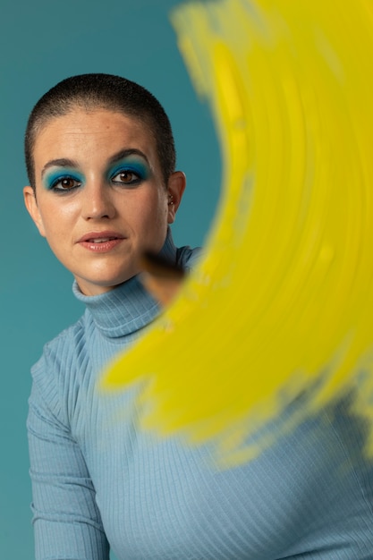 Portrait of beautiful woman posing in a turtleneck with yellow paint brush stroke