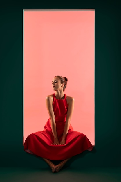 Портрет красивой женщины, позирующей в струящемся красном платье