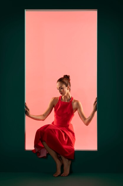Портрет красивой женщины, позирующей в струящемся красном платье