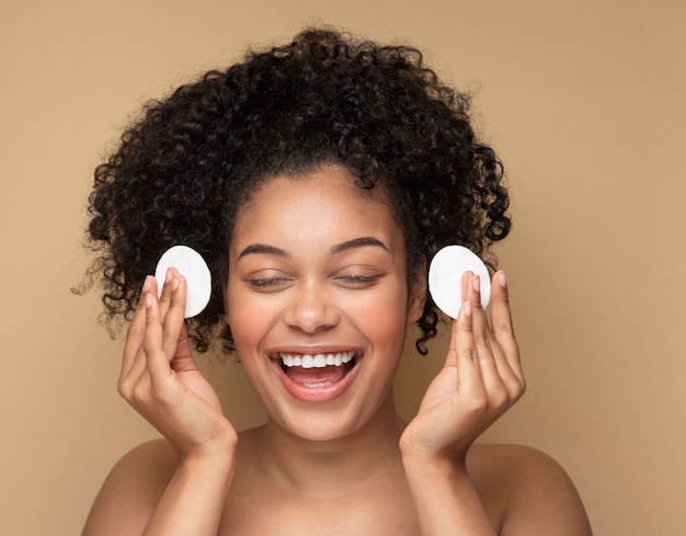 Free photo portrait of a beautiful woman removing her make-up with pads