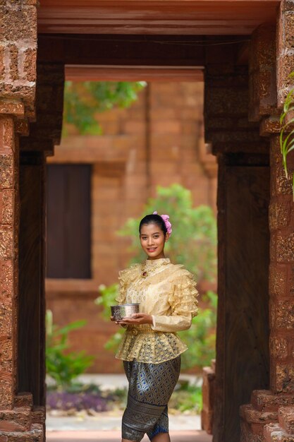 Portrait beautiful woman in Songkran festival with Thai Traditional costume in the temple holding water bowl and smile Thailand culture with Water festival