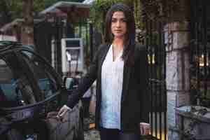 Free photo portrait of beautiful woman standing near car