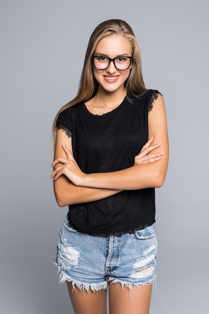 Portrait of a beautiful woman standing with hands folded and looking at camera over gray background