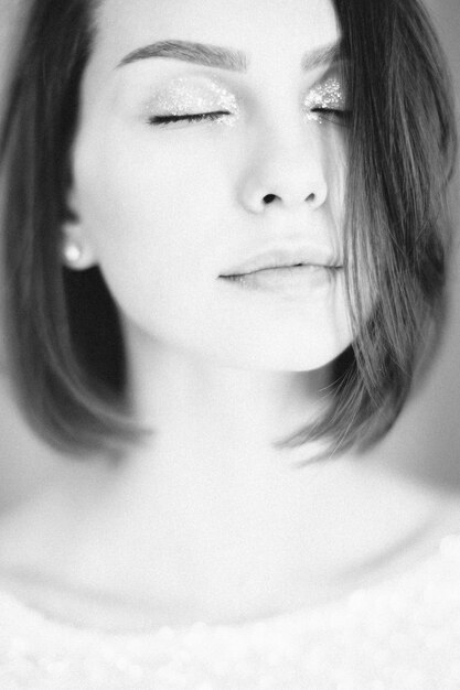 Portrait of beautiful woman thinking with eyes closed in white top. black and white