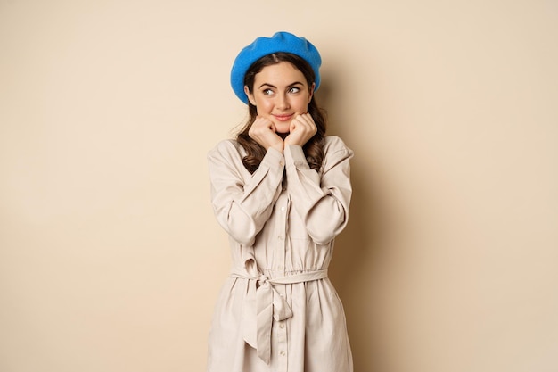 Portrait of beautiful woman in trendy outfit touching her face and looking dreamy yearning smth stan...