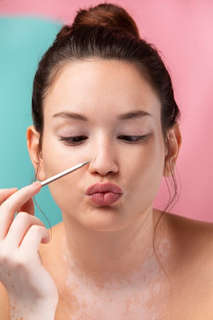 Portrait of a beautiful woman using a pimple tweezers