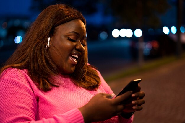 Portrait of beautiful woman using smartphone at night in the city lights