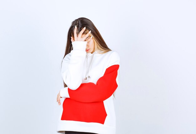 Portrait of a beautiful woman in warm hoodie standing and doing facepalm