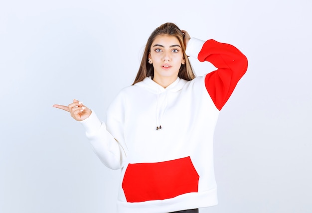 Portrait of a beautiful woman in warm hoodie standing and pointing away