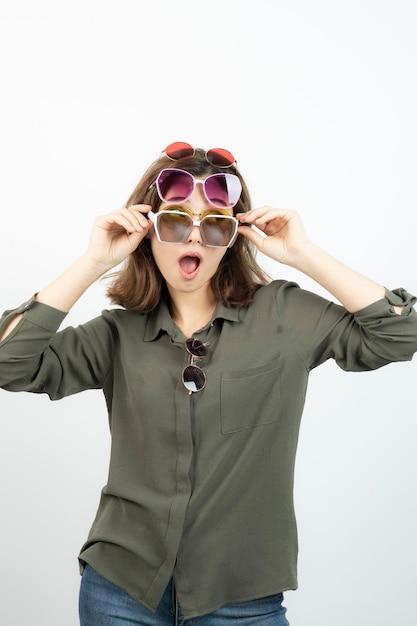 Portrait of beautiful woman wearing many sun glasses over white. High quality photo