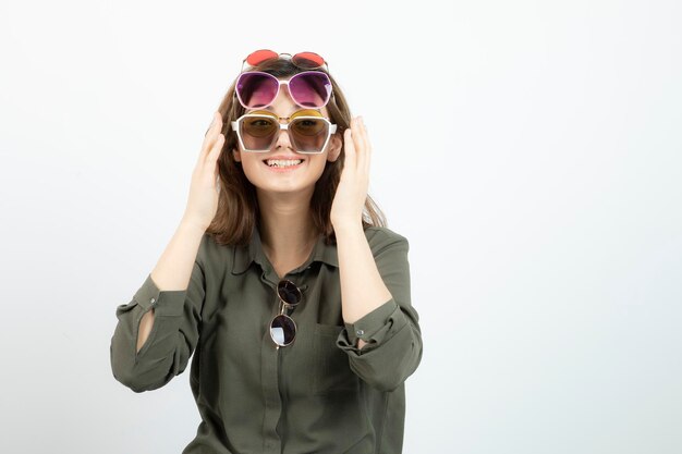 Portrait of beautiful woman wearing many sun glasses over white. High quality photo