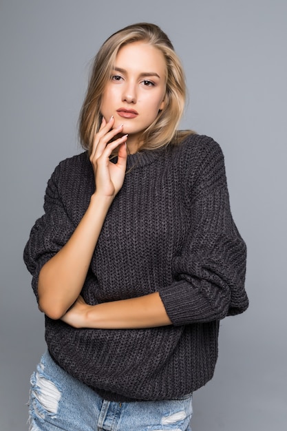 Portrait of a beautiful woman wearing a warm knit sweater on her body on a gray background isolated