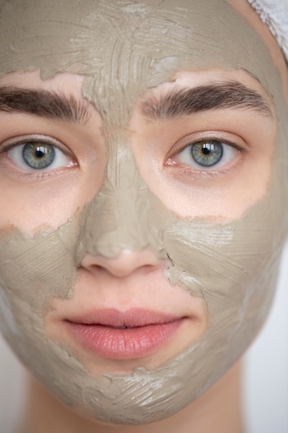 Foto gratuita ritratto di bella donna con maschera di argilla di bellezza sul viso