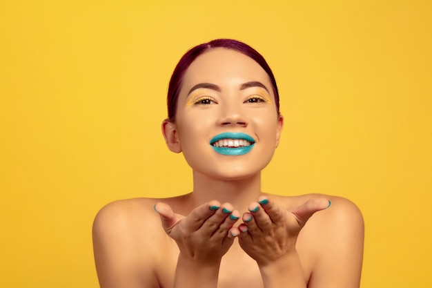 Foto gratuita ritratto di bella donna con trucco luminoso, capelli e manicure su studio giallo