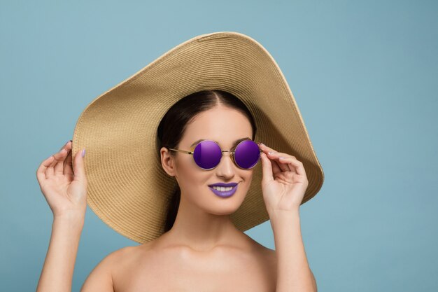 Portrait of beautiful woman with bright make-up, hat and sunglasses. Stylish and fashionable make and hairstyle.