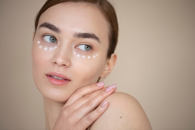 Portrait of beautiful woman with clear skin using under eye cream