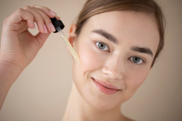 Portrait of beautiful woman with clear skin using face serum