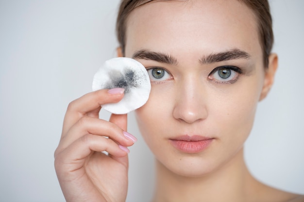 Ritratto di una bella donna con la pelle chiara che usa un tampone struccante per il trucco degli occhi