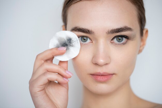 그녀의 눈 화장을 위해 메이크업 리무버 패드를 사용하여 깨끗한 피부를 가진 아름다운 여성의 초상화
