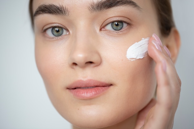 Portrait of beautiful woman with clear skin using moisturizer