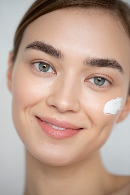 Portrait of beautiful woman with clear skin using moisturizer