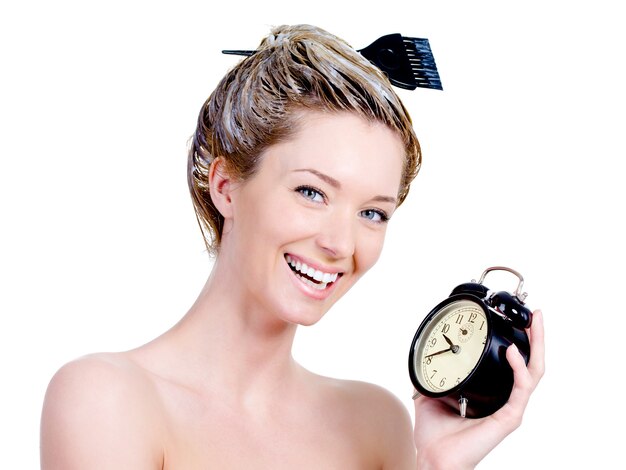 Portrait of beautiful woman with dye on a hair and holding clock - isolated on white