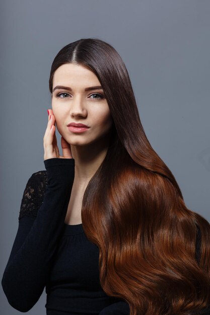 Portrait of beautiful woman with long brown hair posing for photographer. Lady with modern hairstyle posing in studio.