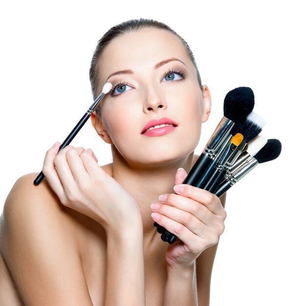 Portrait of the beautiful woman with make-up brushes near attractive face.